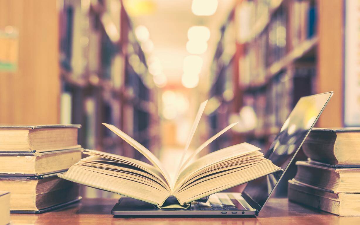 Livro aberto sobre a mesa, entre outros volumes